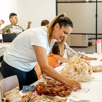 A woman bends down over a table of woven Aboriginal arts and crafts.